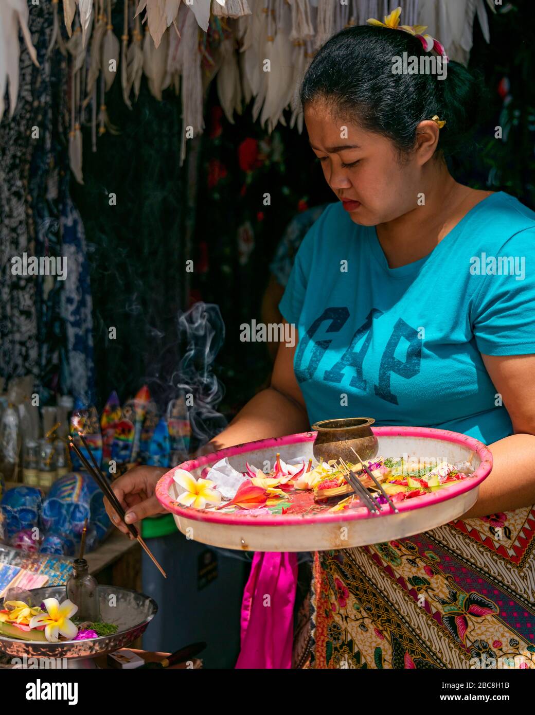 Vertikales Frauenporträt mit Blumen und Weihrauch, um einen neuen Laden in Bali, Indonesien, zu segnen. Stockfoto