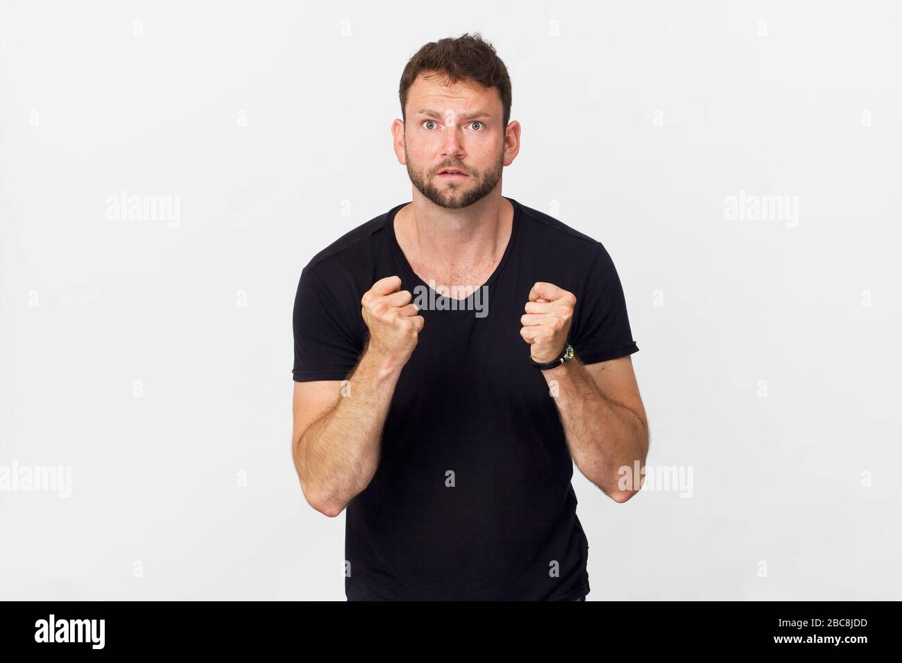 Fröhlicher junger Mann mit gekreuzten Fingern und lächelndem Porträt vor weißem Hintergrund Stockfoto