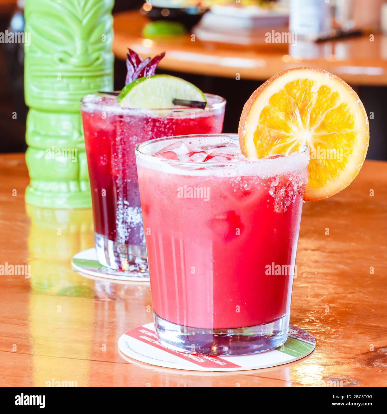 Flug von traditionellen mexikanischen alkoholischen Getränken auf hell glänzenden Holzfläche in traditionellen mexikanischen Restaurant mit orangefarbenen Scheiben rosa rot grünen Getränken Stockfoto