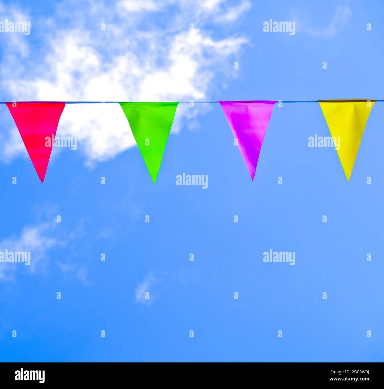 Helle bunte Dreiecksfahnen an einer Schnur, blauer Himmel mit weißen, flauschigen Wolken. Stockfoto