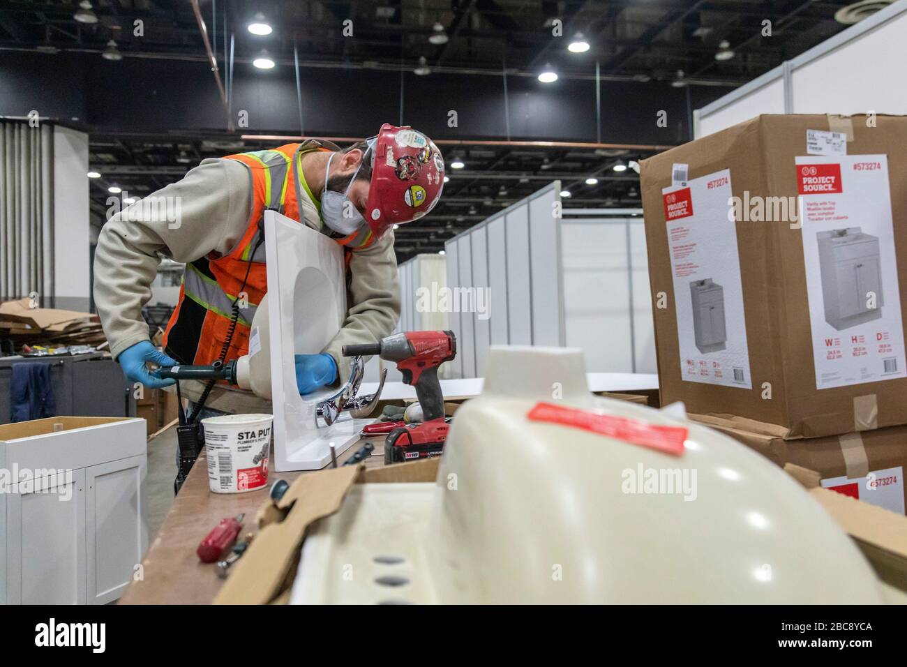 Detroit, Michigan, USA. April 2020. Arbeiter bauen ein Notarztkrankenhaus im TCF-Kongresszentrum auf. Das Krankenhaus mit 1.000 Betten wird Covid-19-Patienten versorgen. Ein Installateur stellt Waschbecken für Händewaschstationen zusammen. Kredit: Jim West/Alamy Live News Stockfoto