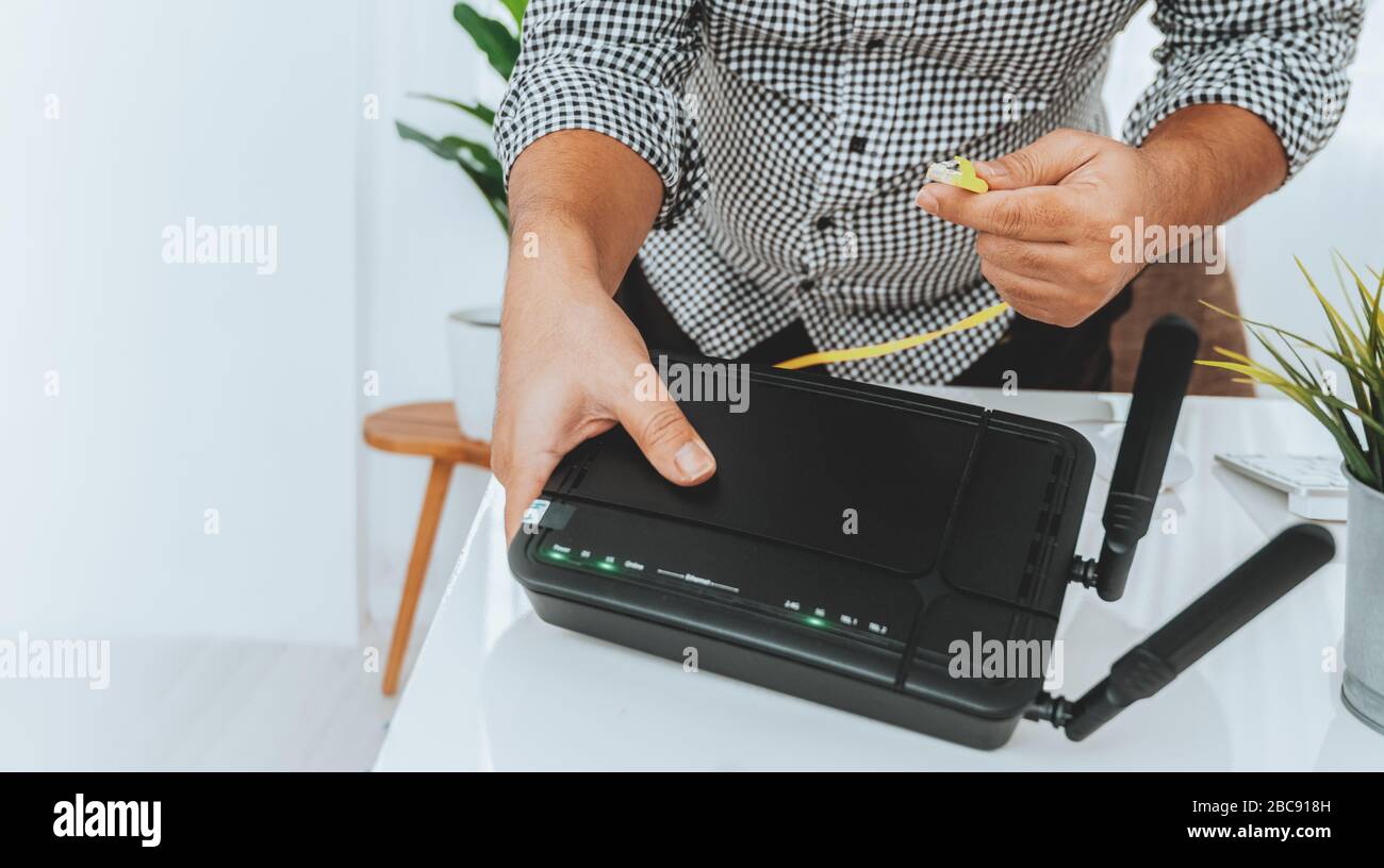 Hand- und lan-Netzwerkkabel mit Mitarbeitern arbeiten am Wireless-Router, Mann arbeitet von zu Hause aus, während er sich während der Covid-19-Gesundheitskrise in Quarantäne befindet Stockfoto