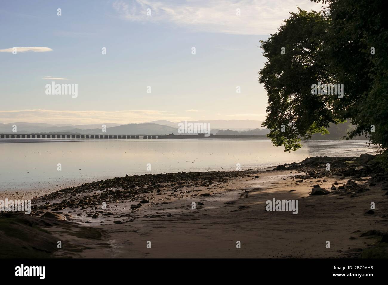 Der Tempolimit der Northern Rail Klasse 142 nähert sich kurz nach Sonnenaufgang im Sommer dem Arnside-Viadukt mit den dahinter liegenden Hügeln im Seebezirk Stockfoto
