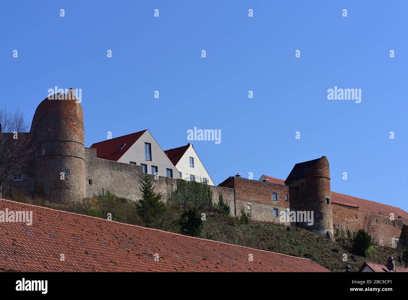 Historische Stadtmauer Friedbergs in Bayern mit Türmen gegen blauen Himmel und mit Kacheln überzogenen Dächern Stockfoto