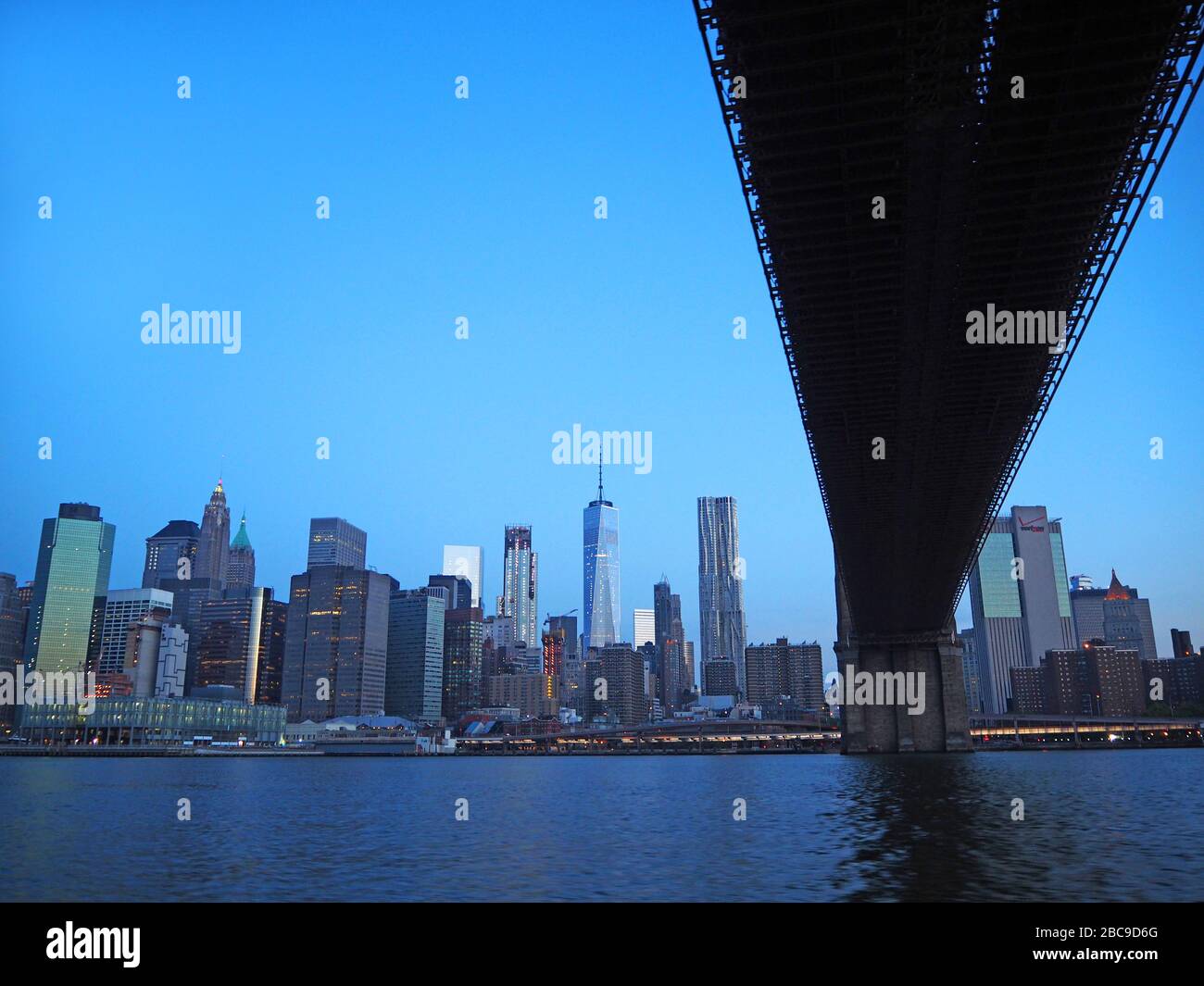 Unter der Brooklyn Bridge, mit einem World Trade Center und Lower Manhattan im Morgengrauen, vom East River, Manhattan, New York, USA aus gesehen Stockfoto