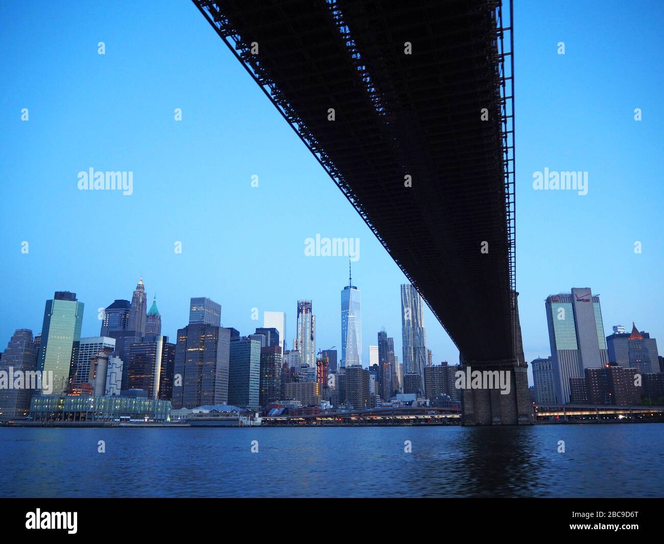 Unter der Brooklyn Bridge, mit einem World Trade Center und Lower Manhattan im Morgengrauen, vom East River, Manhattan, New York, USA aus gesehen Stockfoto