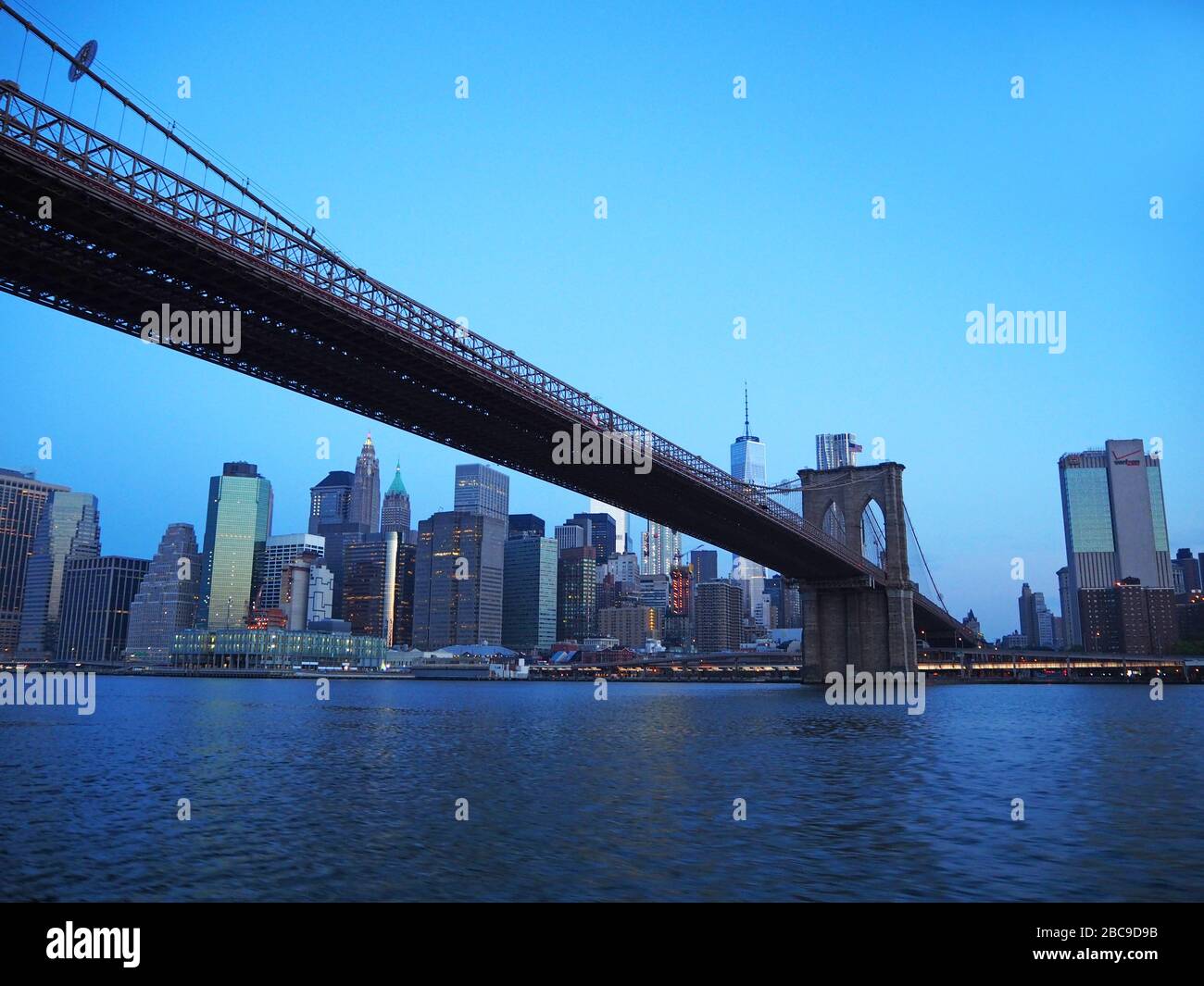 Unter der Brooklyn Bridge, mit einem World Trade Center und Lower Manhattan im Morgengrauen, vom East River, Manhattan, New York, USA aus gesehen Stockfoto