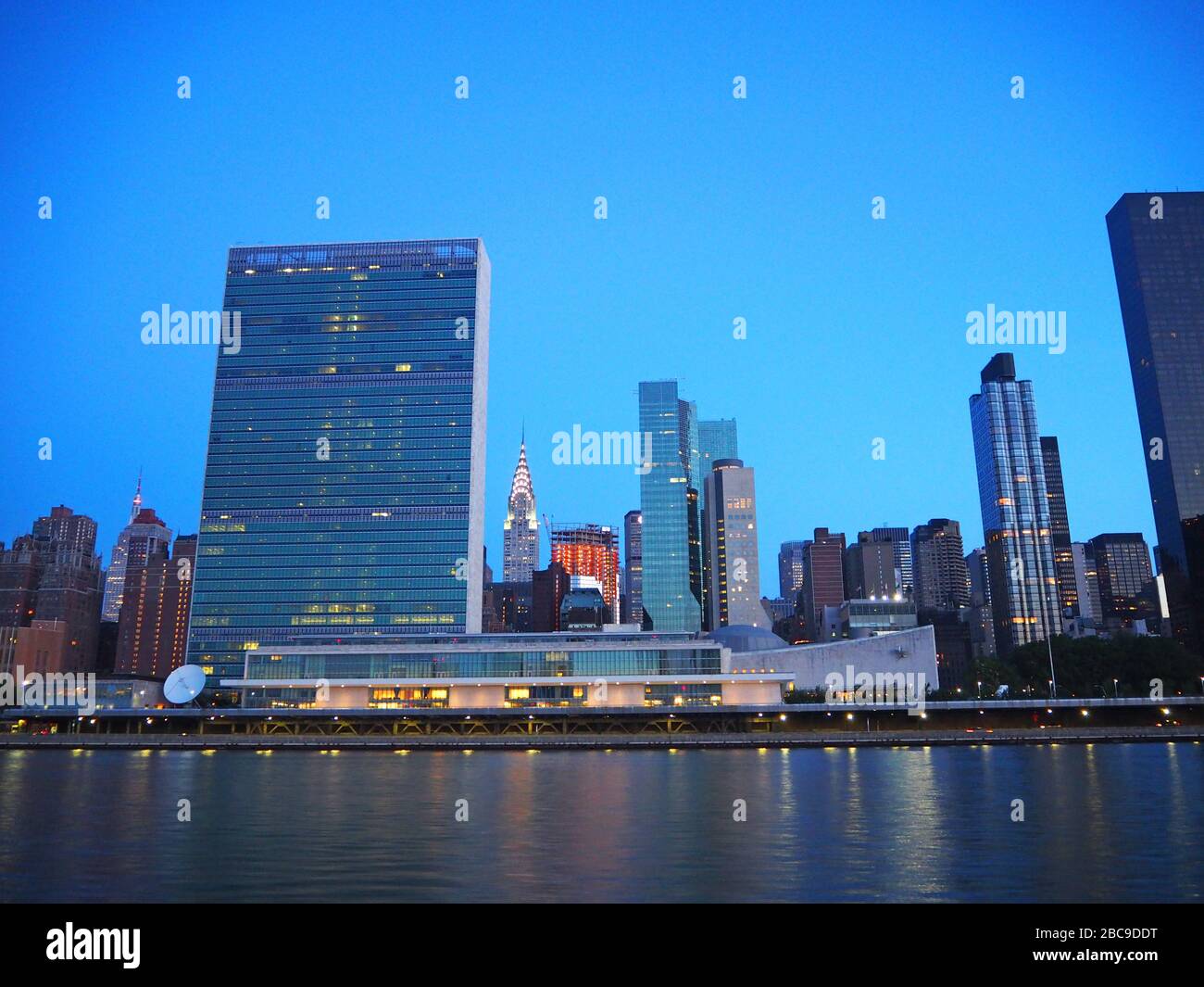 Gebäude des Hauptquartiers der Vereinten Nationen mit Chrysler Building im Hintergrund im Morgengrauen, vom East River, New York, USA aus gesehen Stockfoto
