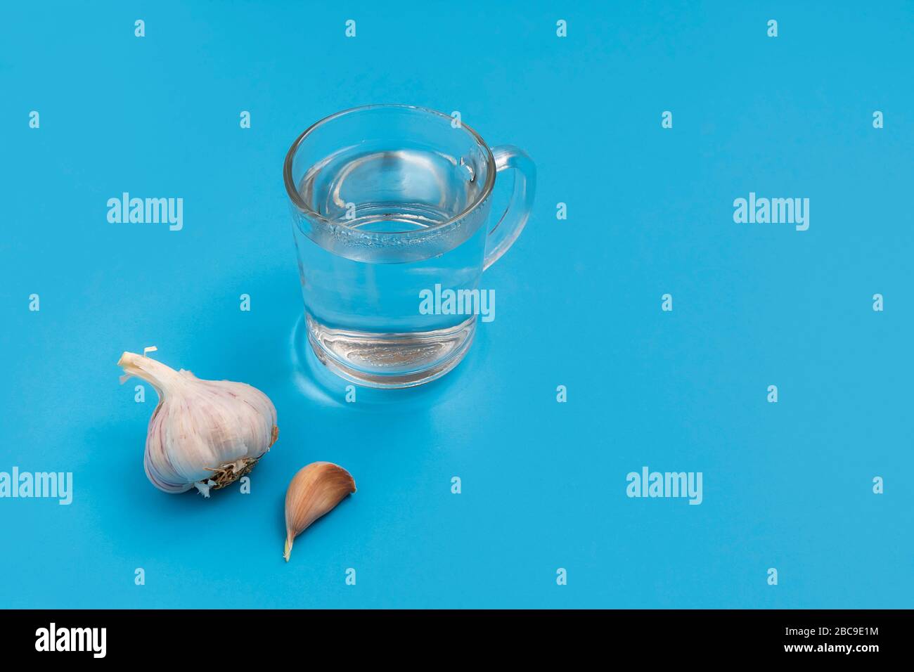 Coronavirus- oder Gesundheits-Mythen: Heißes Wasser trinken und Knoblauch essen, blauer Hintergrund Stockfoto Coronavirus- oder Gesundheits-Mythen: Heißes Wasser trinken und Knoblauch essen, blauer Hintergrund Stockfoto