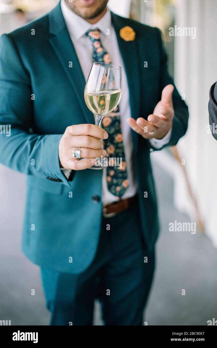 Weißwein in der Hand des Menschen im blauem Anzug Stockfoto