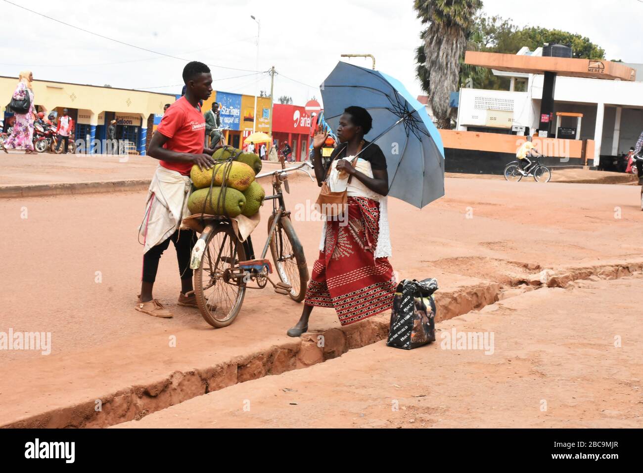 Ein männlicher Händler und eine Frau verhandeln auf der Straße in der Stadt Rwamagana, Ruanda, über die Preise für Jackfruits Stockfoto