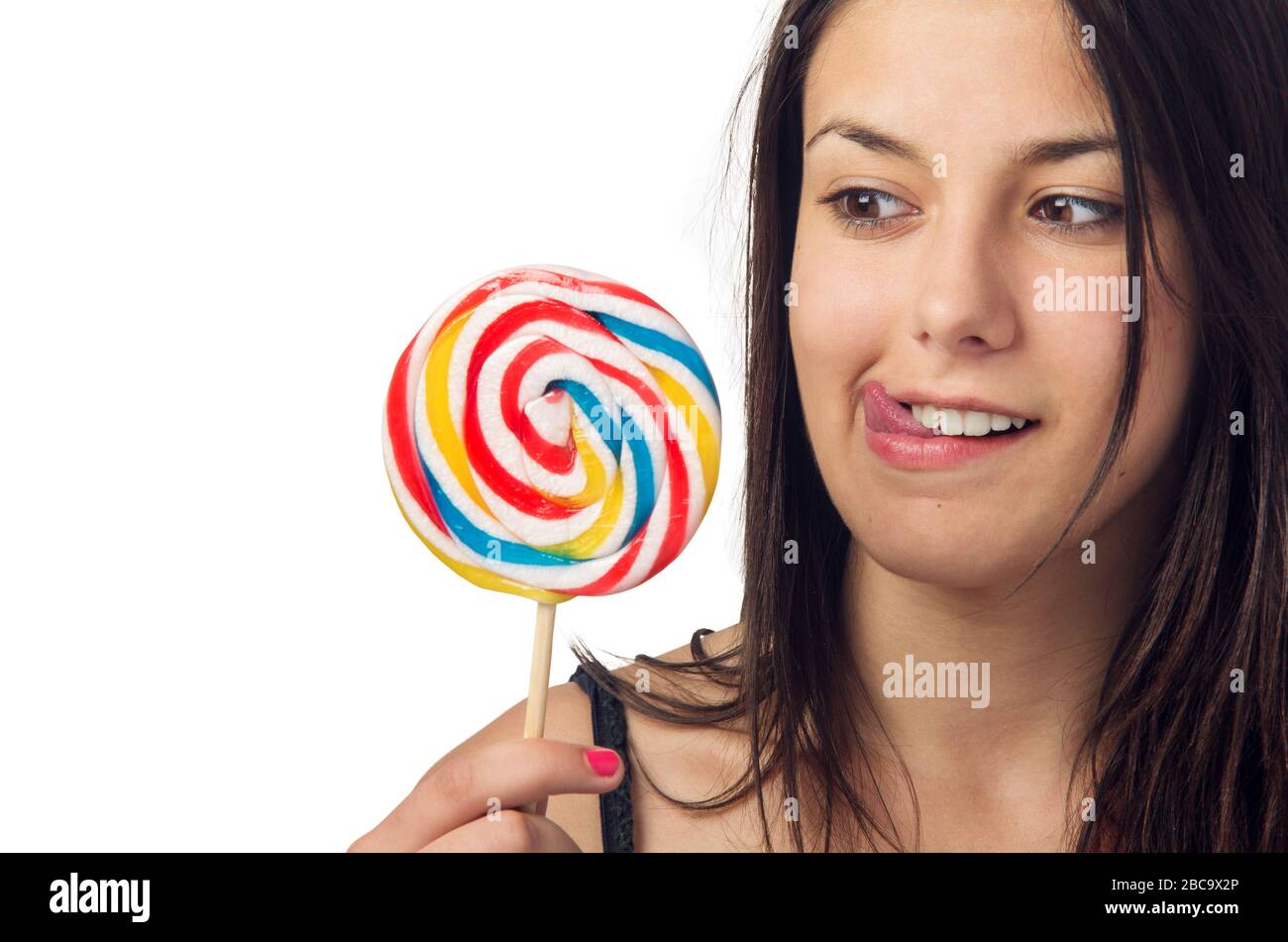 Ziemlich brünette Teenager, die auf ihren großen und süßen Lollipop eifrig sind Stockfoto