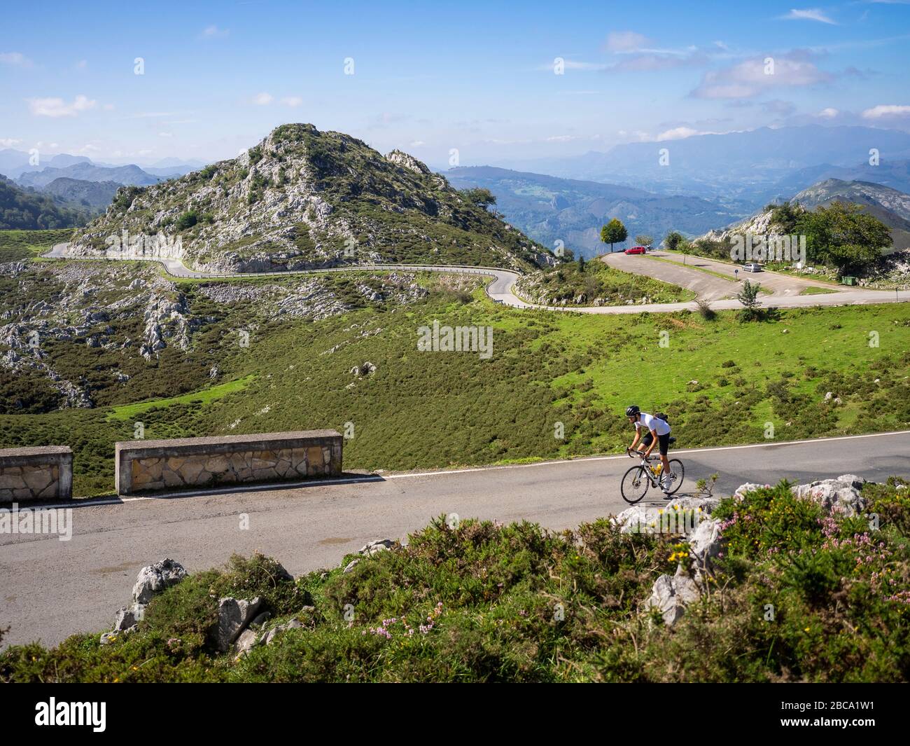 Straßenradsport in Asturien, Nordspanien. Rennradrennfahrer auf einer steilen Bergstraße in der Nähe des Lagos de Covadonga. Im Hintergrund der Aussichtspunkt Mirado Stockfoto