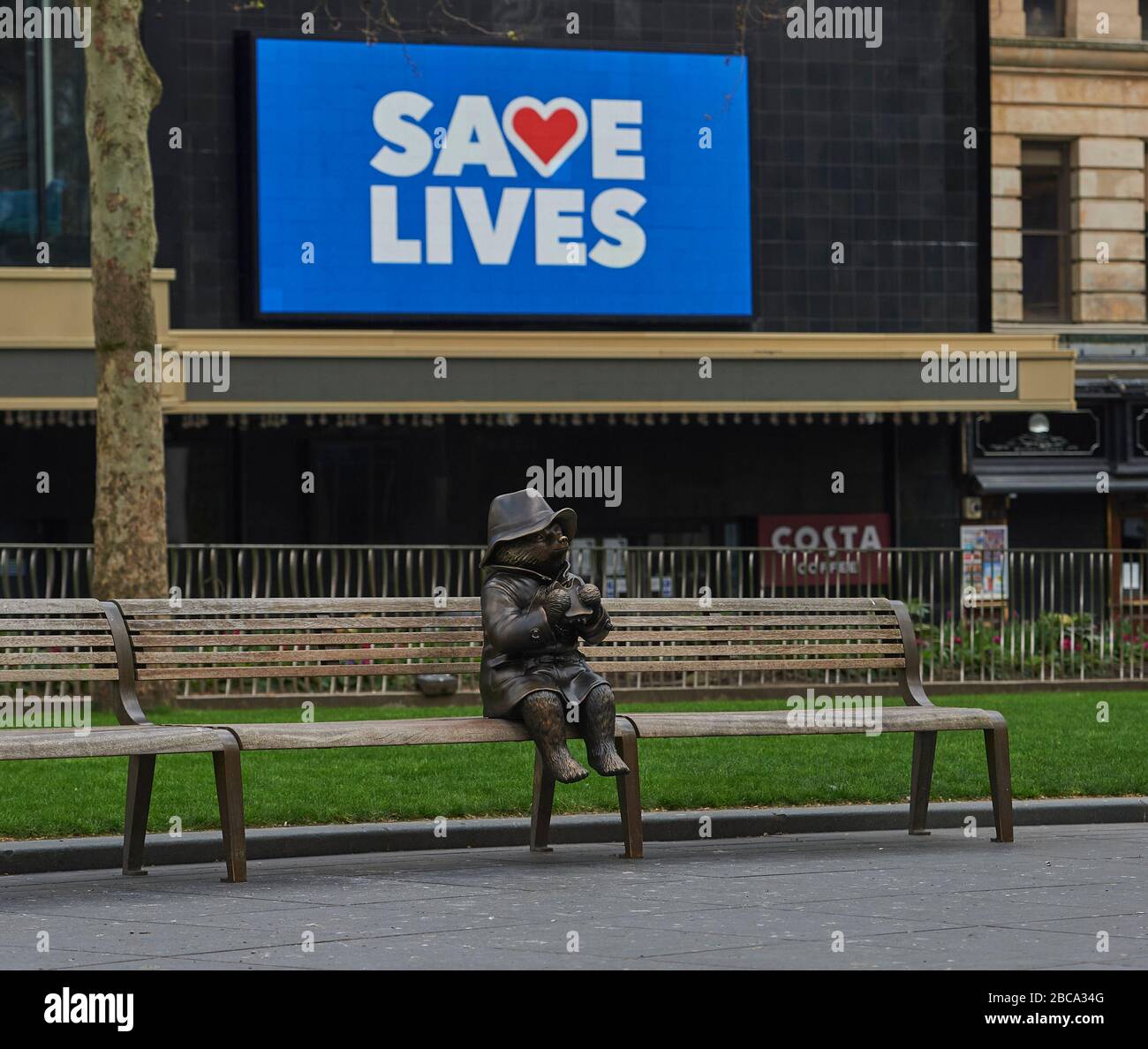 London. GROSSBRITANNIEN. April 2020. Eine Bronzestatue des Paddington-Bären sitzt allein auf einer Bank am Leicester Square, mit Nachrichten für die NHS auf den Bildschirmen des Odeon-Kinos während der Global Pandemy Credit: Thomas Bowles/Alamy Live News Stockfoto