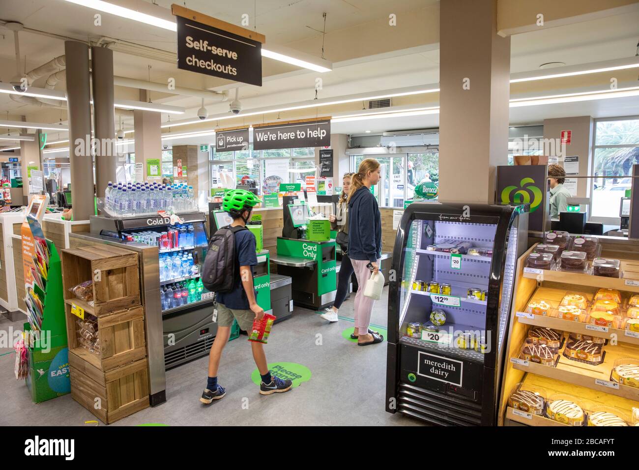 Coronavirus Risk, Junge und Mädchen stehen hier auf den Fußbodenmarkierungen in einem australischen Supermarkt, um soziale Distanzierungen zu erhalten Stockfoto