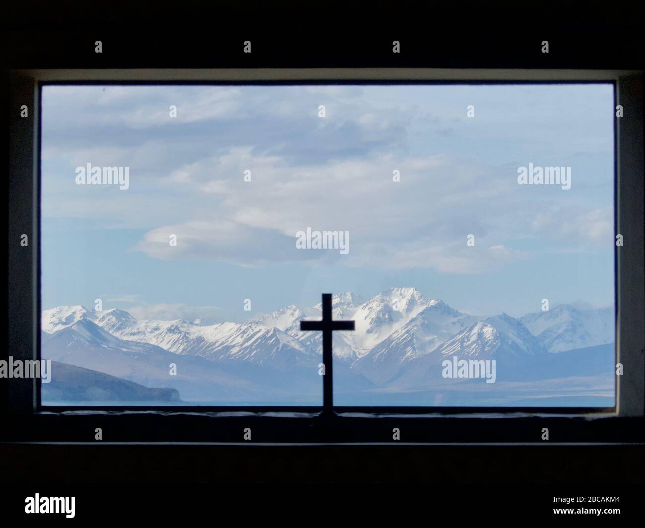 Blick durch das Fenster der Kirche des Guten Hirten über den Tekapo See in die Südlichen Alpen mit Kruzifix im Vordergrund Stockfoto