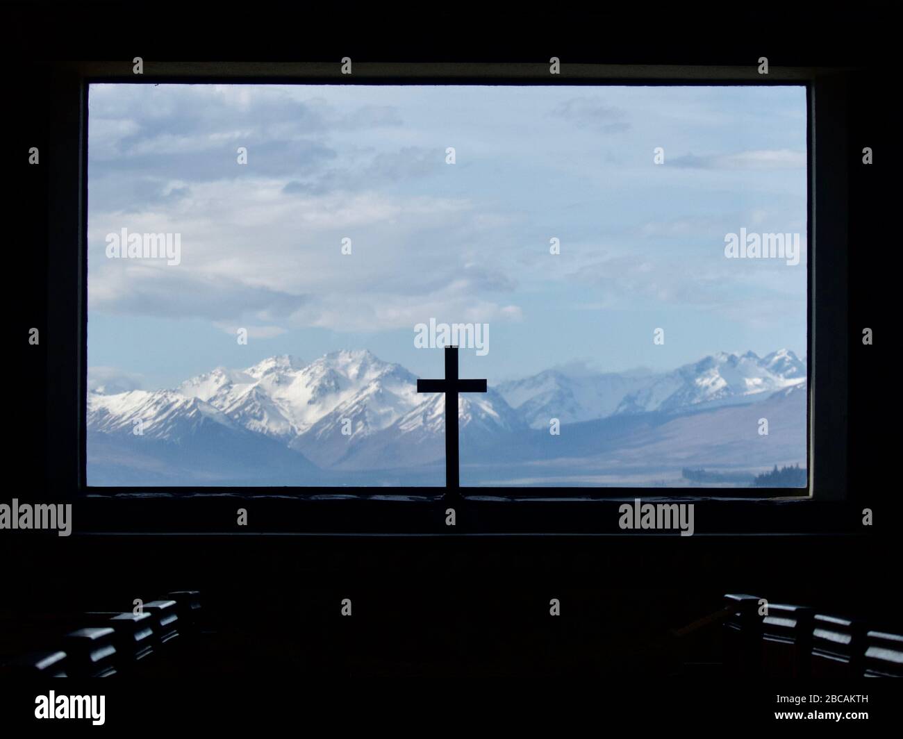Blick durch das Fenster der Kirche des Guten Hirten über den Tekapo See in die Südlichen Alpen mit Kruzifix im Vordergrund Stockfoto