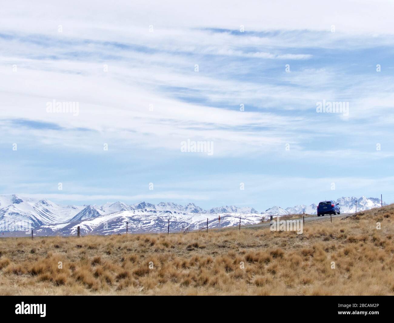 Ein Auto fährt in Tekapo mit Blick auf die südlichen Alpen im Hintergrund Stockfoto