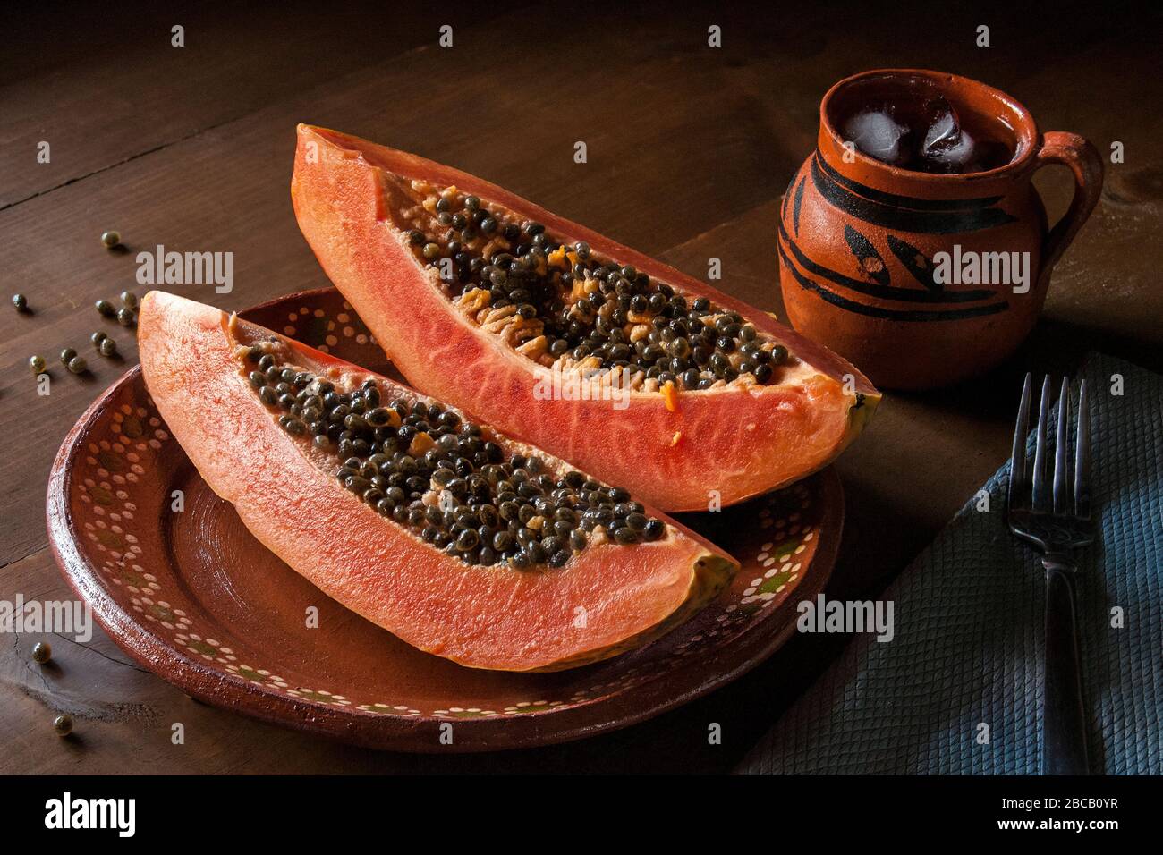Papaya Auf Einer Mexikanischen Schlamm Oder Tonplatte Mit Einem Mexikanischen Glas Eiswasser Auf Einem Rustikalen Holztisch In Dunkler Lebensmittelfotografie Oder Schwachem Licht Stockfotografie Alamy