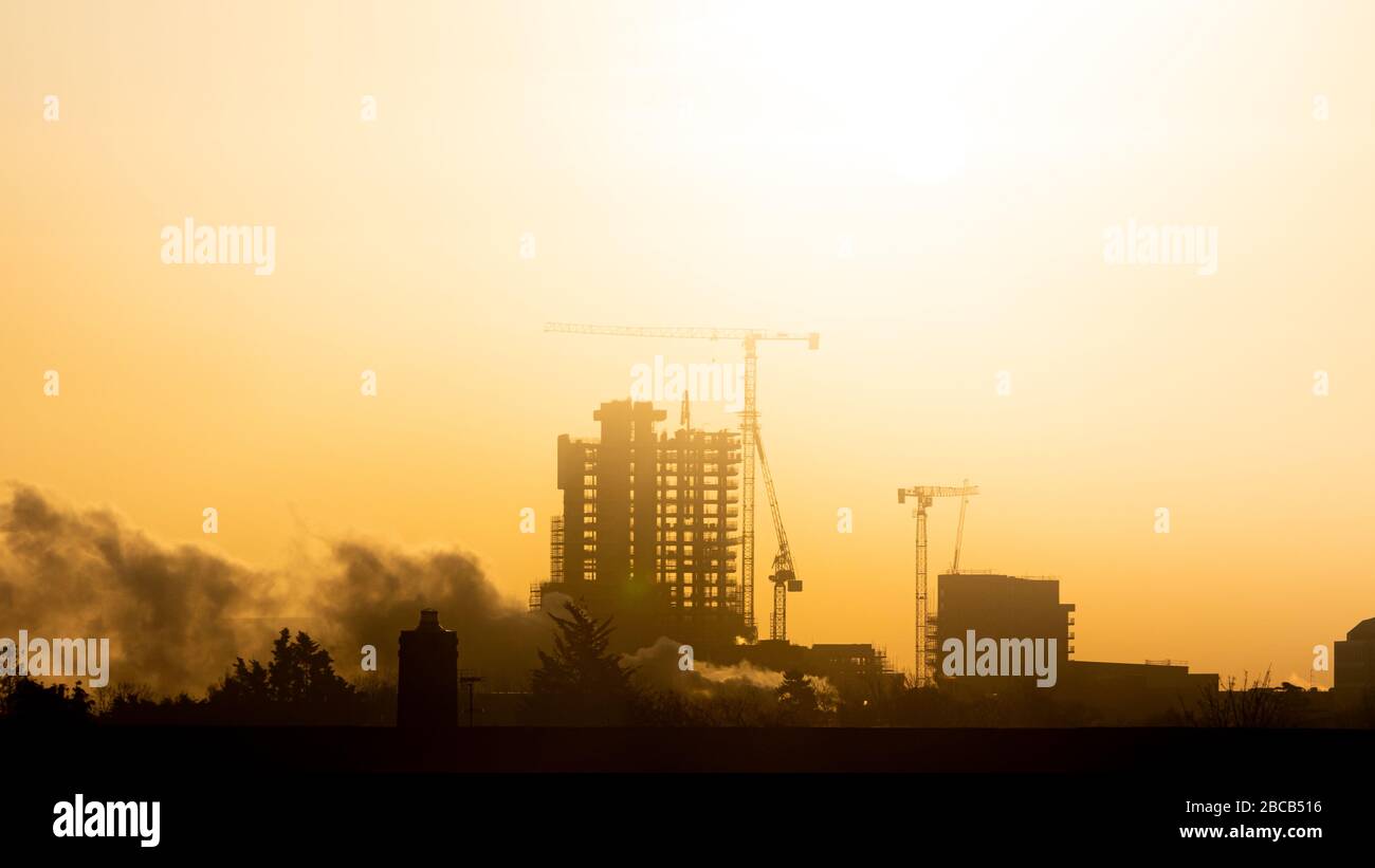 Dampf steigt über den Dächern auf, während die Sonne durch einen nebligen Himmel über der westlichen Skyline Londons scheint Stockfoto Dampf steigt über den Dächern auf, während die Sonne durch einen nebligen Himmel über der westlichen Skyline Londons scheint Stockfoto