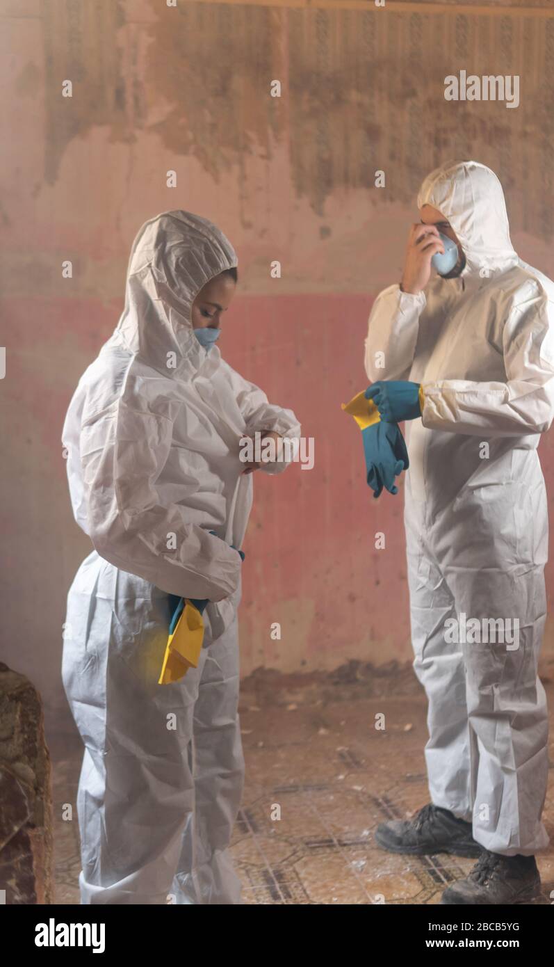 Ein paar Wissenschaftler Virologen immer mit einem weißen Schutzisolierung Biohazard Anzug in einem kontaminierten Haus durch Viren und Strahlung angezogen Stockfoto