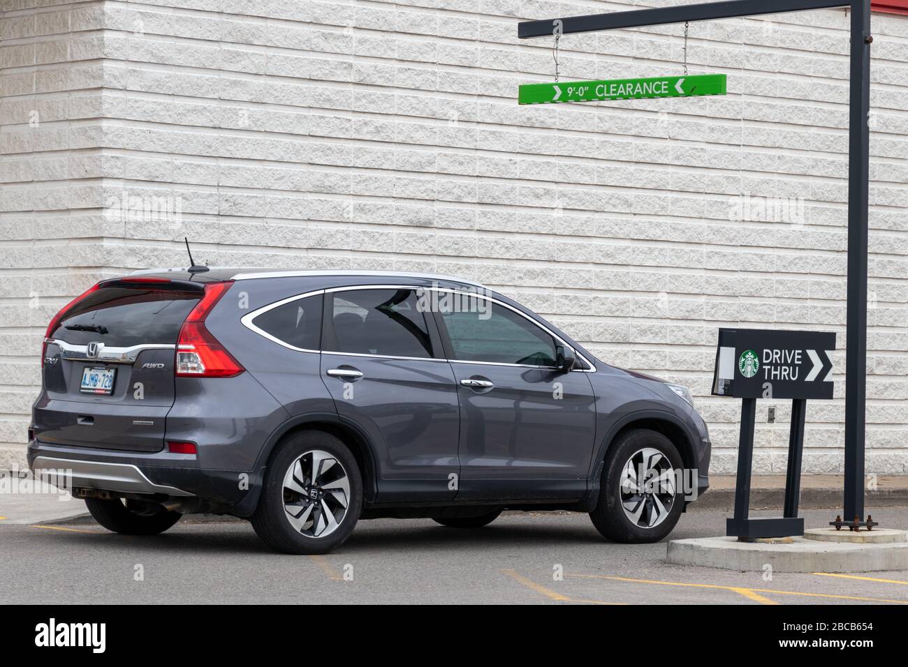 Das Auto betritt den Drive-Thru-Pfad zum Starbucks Coffee Shop, Schild neben dem Auto. Stockfoto