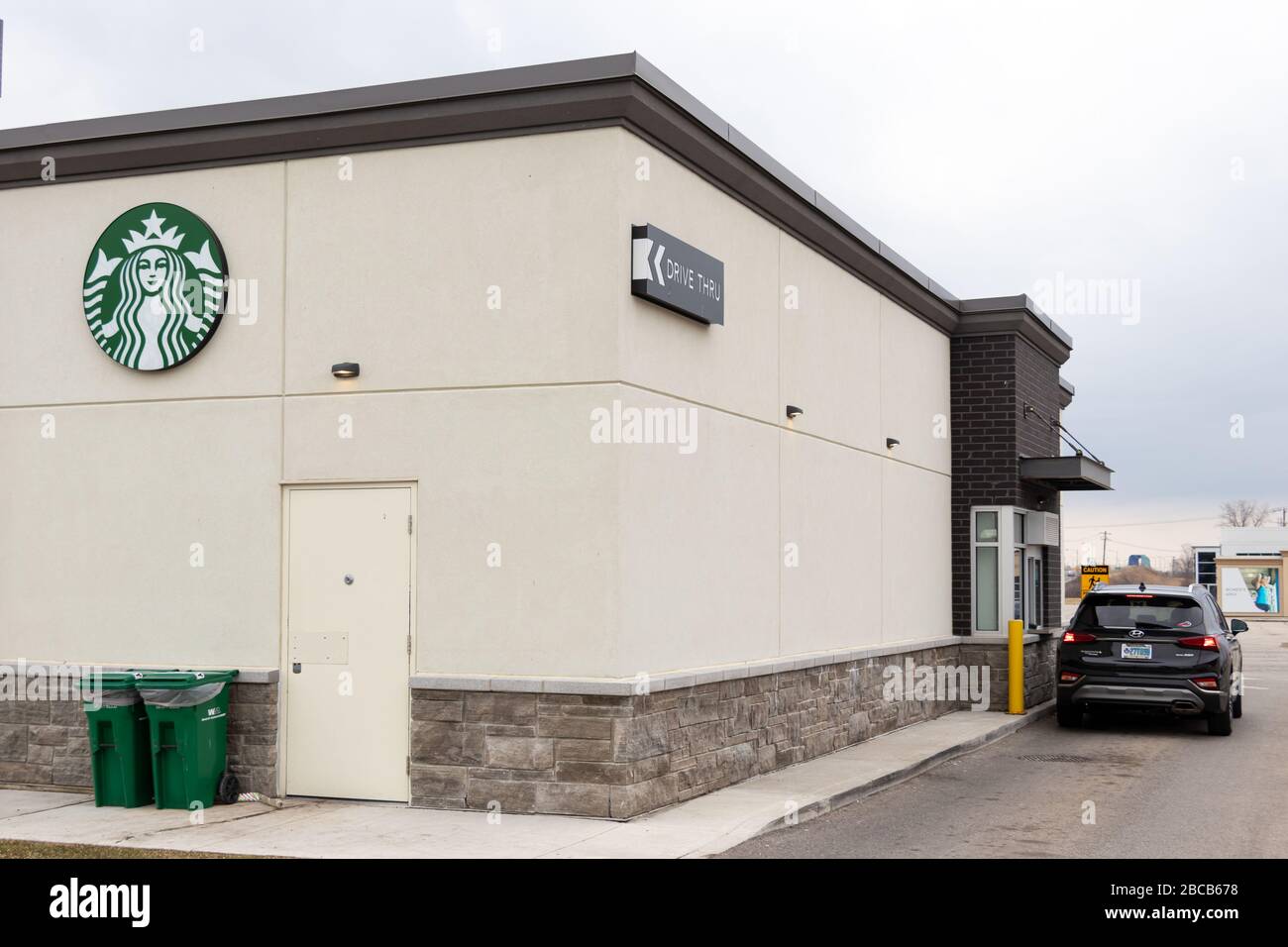 Starbucks Coffee Schild auf der Rückseite eines Ladens, das mit einem Auto am Drive-Thru-Fenster zu sehen ist. Stockfoto