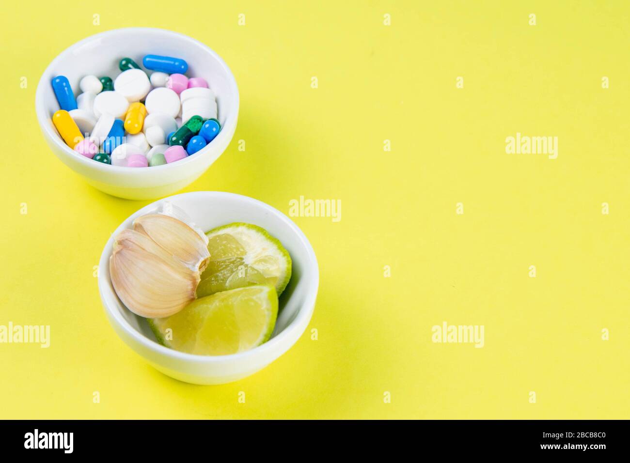 Kalk und Ingwer gegen mehrfarbige Tabletten. Das Konzept der Wahl einer gesunden Ernährung im Gegensatz zur Einnahme von Medikamenten. Draufsichten mit klarem Raum Stockfoto