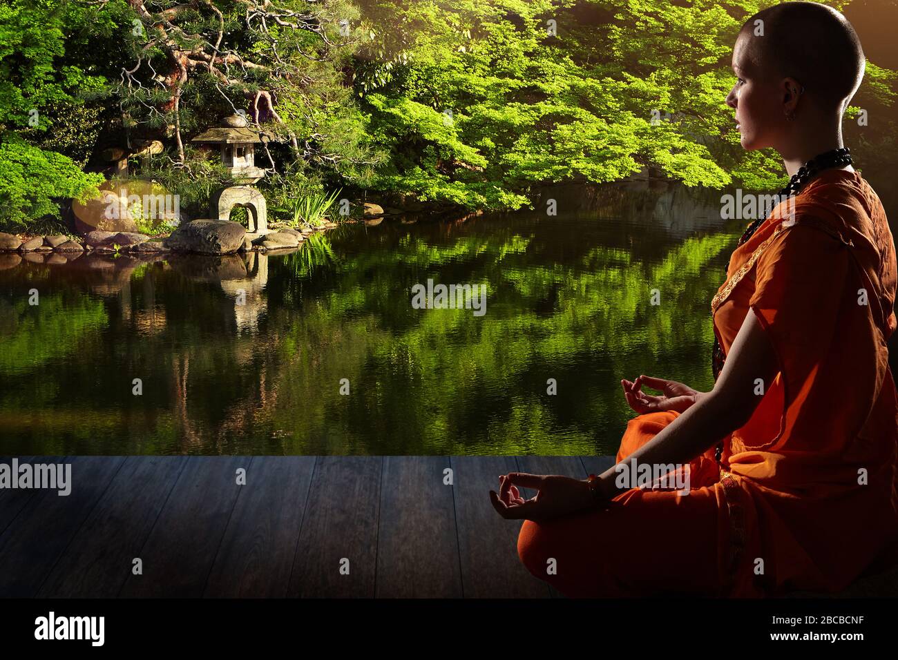 Schöne junge Frau in orange Robe sitzt in Meditation im Garten auf Holzboden..Meditation ist der beste Weg, um das komplexeste Problem zu lösen. Stockfoto