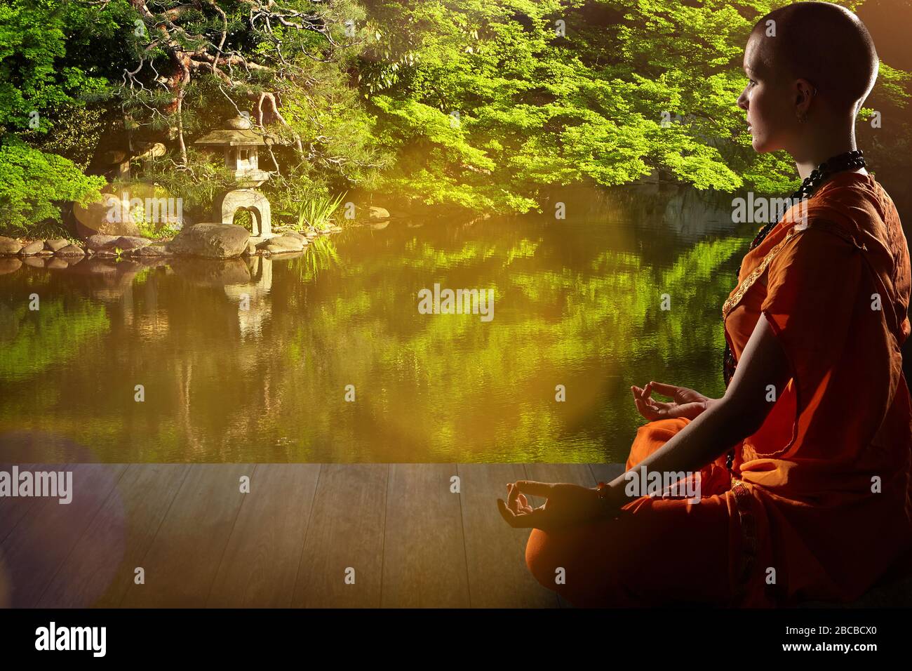 Schöne junge Frau in orange Robe sitzt in Meditation im Garten auf Holzboden..Meditation ist der beste Weg, um das komplexeste Problem zu lösen. Stockfoto