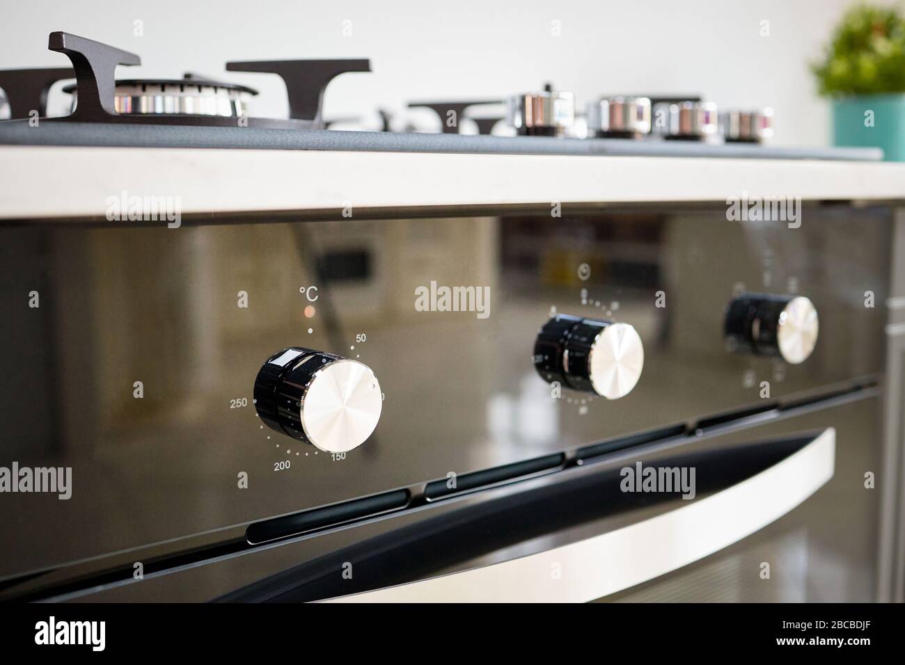 Modernes, klassisches Design mit integriertem Ofen und Gasherd in dunklen Farbtönen unter hellem Arbeitsplatte im Inneren der modernen Küche. Stockfoto