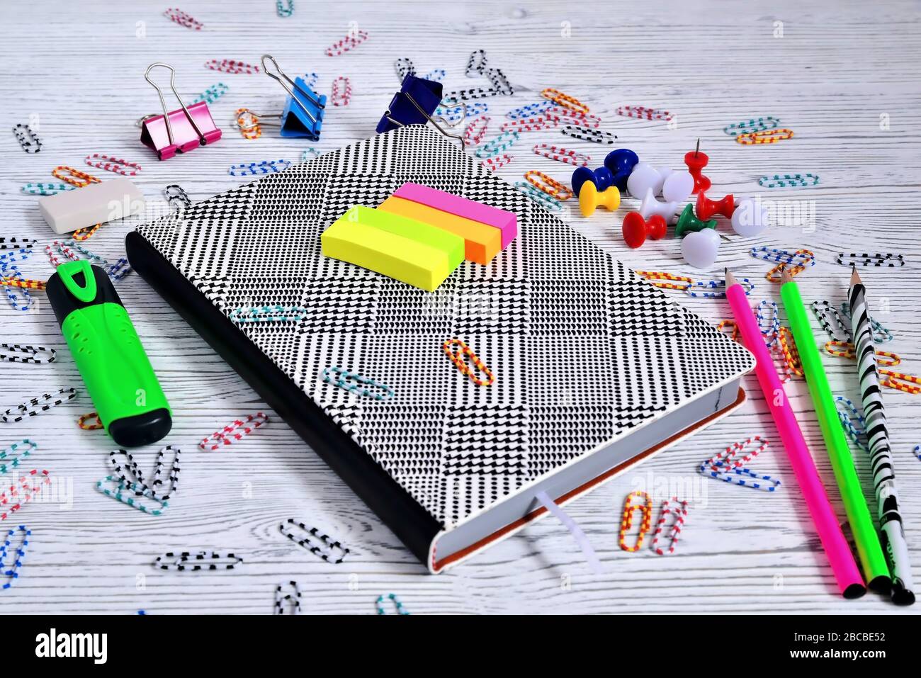 Notizblock, Büroklammern, Knöpfe, Bleistifte, Marker auf hellem Hintergrund Stockfoto