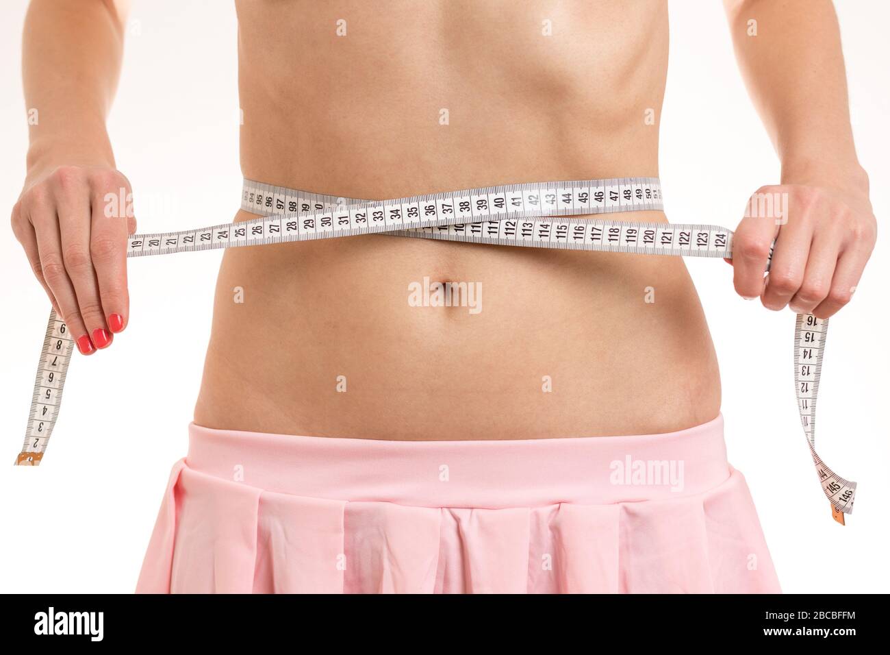 Slim Mädchen mit rosa Rock misst ihre dünne Taille mit einem Band Maßnahme. Lizenzfreies Stock Foto. Stockfoto