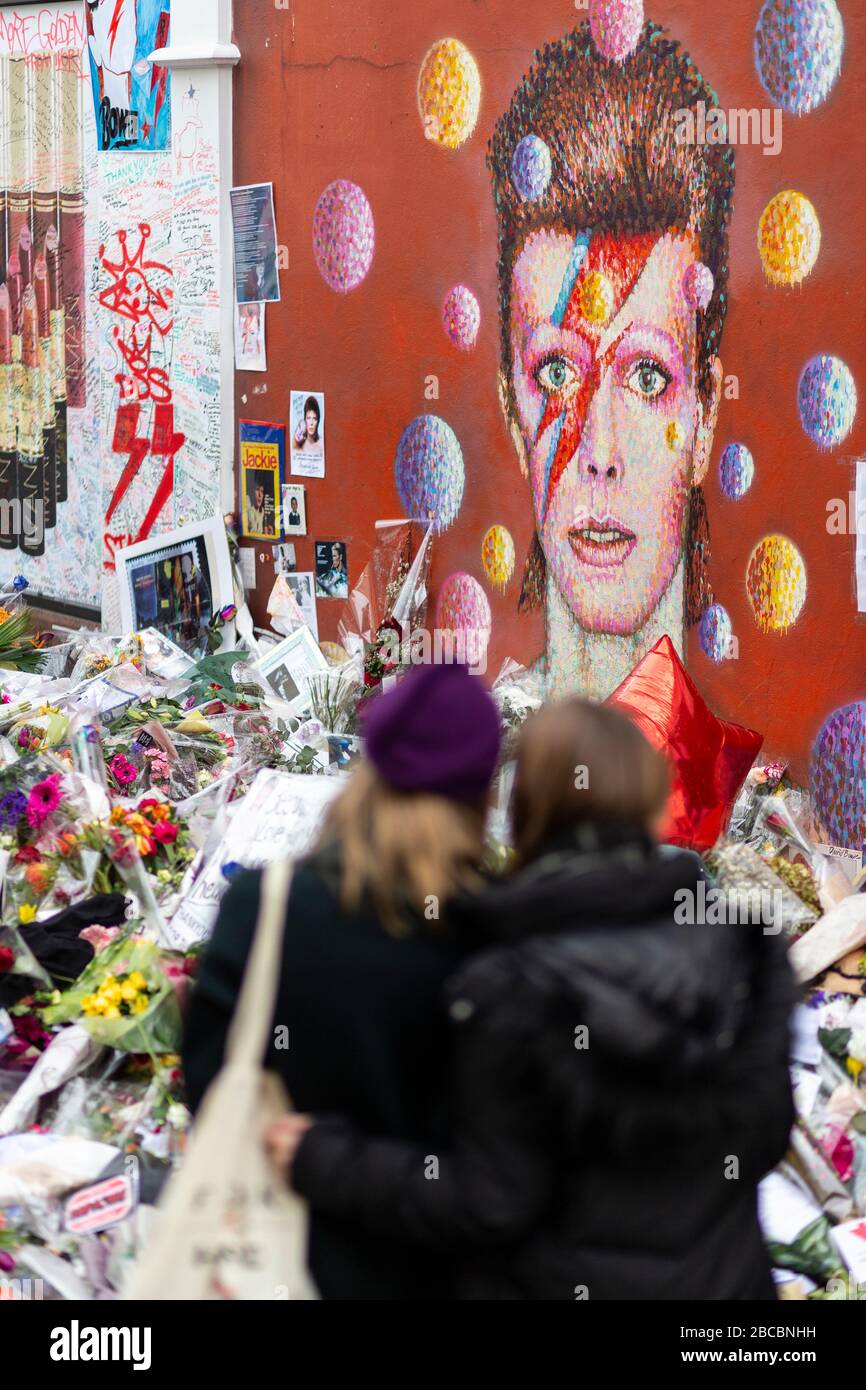 Wandgemälde von David Bowie in Brixton umgeben von Gedenkopfern, die unmittelbar nach seinem Tod in London gelegt wurden Stockfoto