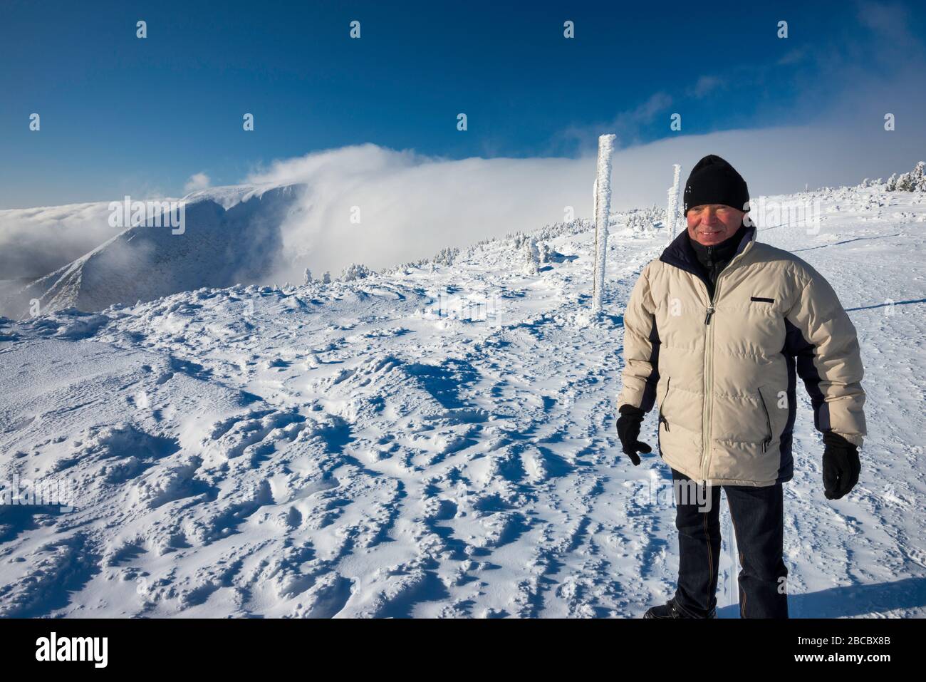 Mann in den Sechzigern im Winter in Karkonosze (Riesengebirge) wandern, Föhn Wolke, Sudetengebirge, Nationalpark Karkonosze, Niederschlesien, Polen Stockfoto