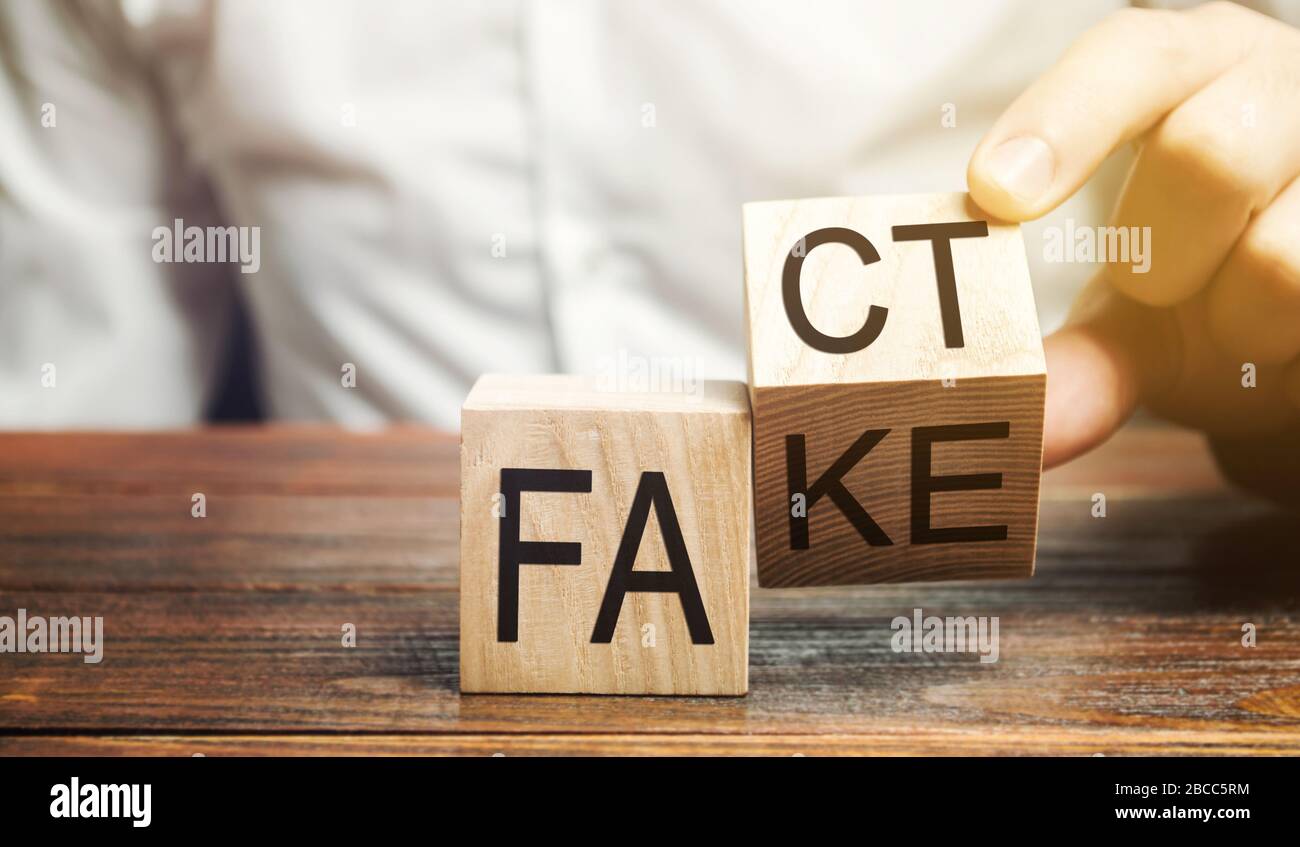 Ein Mann stellt Holzblöcke mit den Worten Fakt und Fake. Konzept von Nachrichten und falschen Informationen. Gelb drücken. Stockfoto