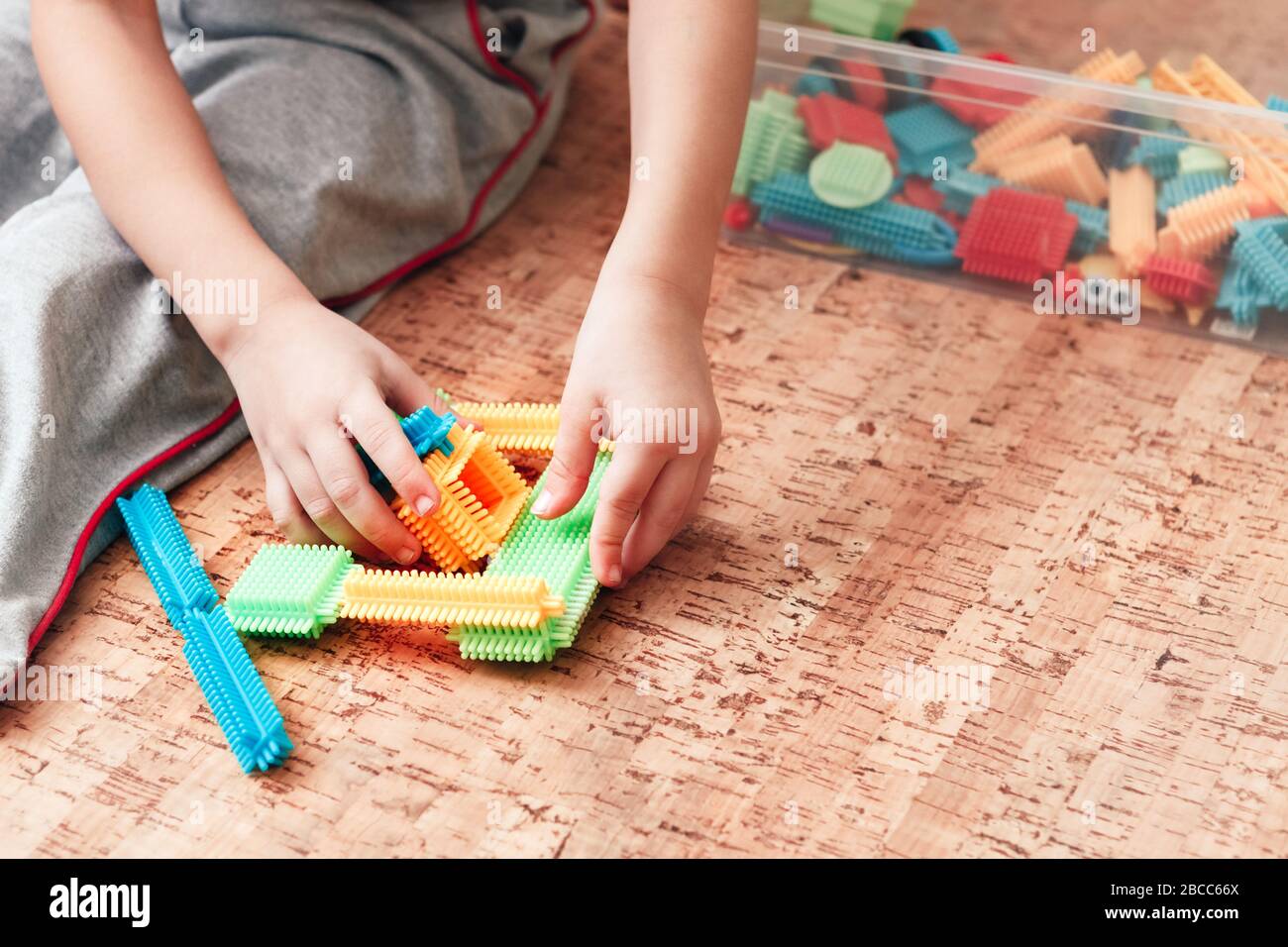 Eine Nahaufnahme eines Kindes, das mit einem Nadelkonstruktor spielt, der die Phantasie fördert und seine Fingerspitzen massiert, um feine motorische Fähigkeiten zu entwickeln. Stockfoto
