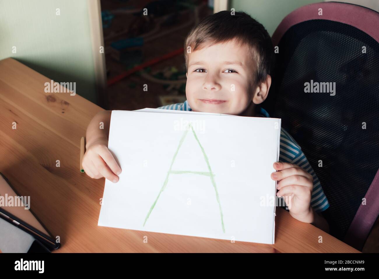 Glücklich zufrieden Junge zeigt Seite mit handgeschriebenen Brief A, Home Bildung Konzept Stockfoto