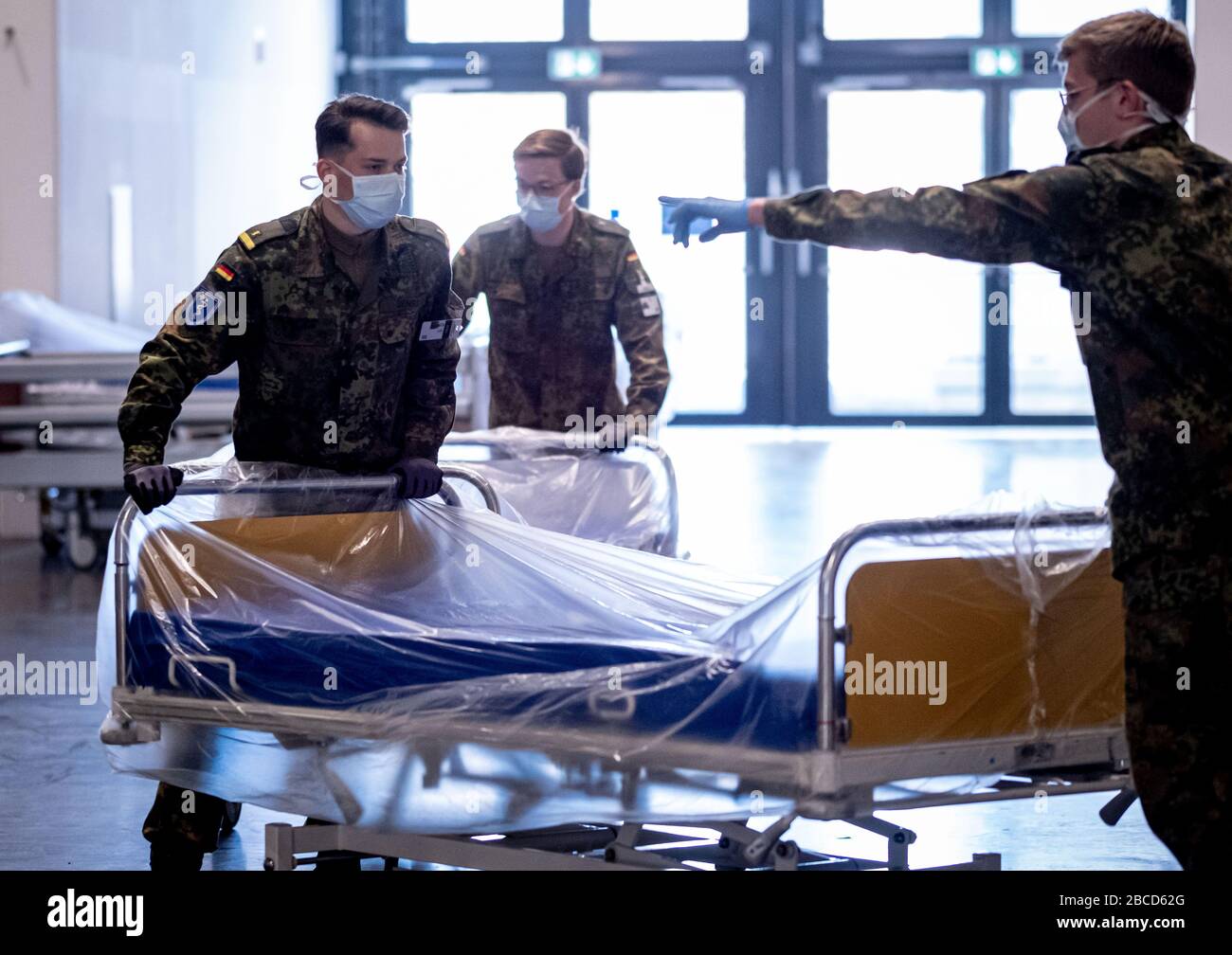 Hannover, Deutschland. April 2020. Soldaten, die Gesichtsmasken tragen, bringen Krankenhausbetten in die provisorische Klinik auf dem Messegelände, die am selben Tag von Ministerpräsident weil besucht wurde. Die Maßnahmen zur Eindämmung des Virus zeigen derzeit weniger Wirkung als gewünscht. Kredit: Peter Steffen / dpa / Alamy Live News Stockfoto