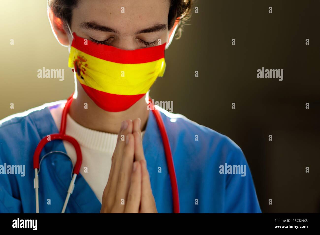 Betet für Spanien. Arzt in Gesichtsmaske betend. Medizinisches Personal in der Krankenhauskapelle oder Kirche bei Ausbruch des Coronavirus. Virus-Pandemie. Die Menschen beten. Kindergärten Stockfoto