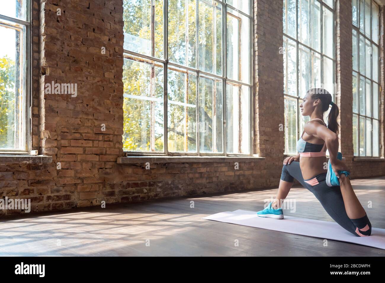 Fit Woman Fitnesstrainer tragen BH-Hosen auf der Matte in der Sporthalle aufwärmen. Stockfoto