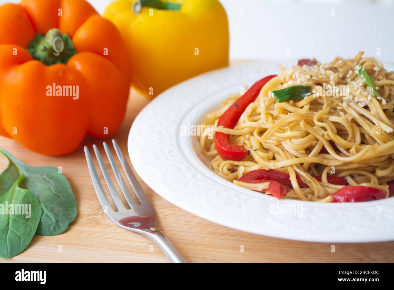 Chinesische Eiernudeln in Sojasauce mit bunten Paprika, Grüns und Frühlingszwiebeln mit Sesamsamen darauf gestreut Stockfoto