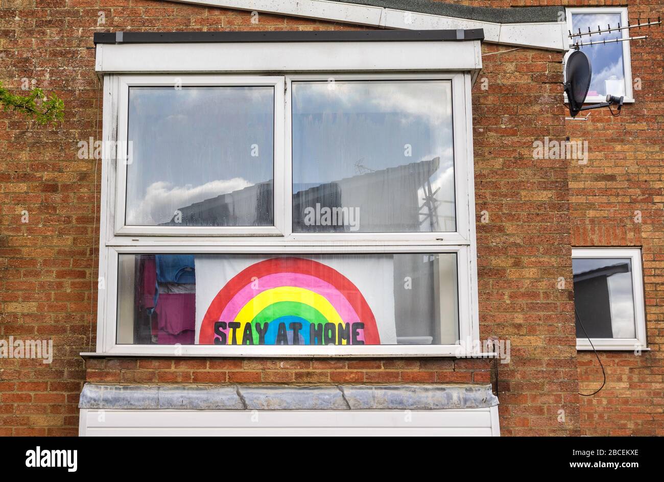 Banner mit einer "Day at home message" und einem Regenbogen, der in einem Fenster auf dem Höhepunkt der Coronavirus-Pandemie während der Sperre im April 2020 in Southampton, England, Großbritannien, angezeigt wird Stockfoto