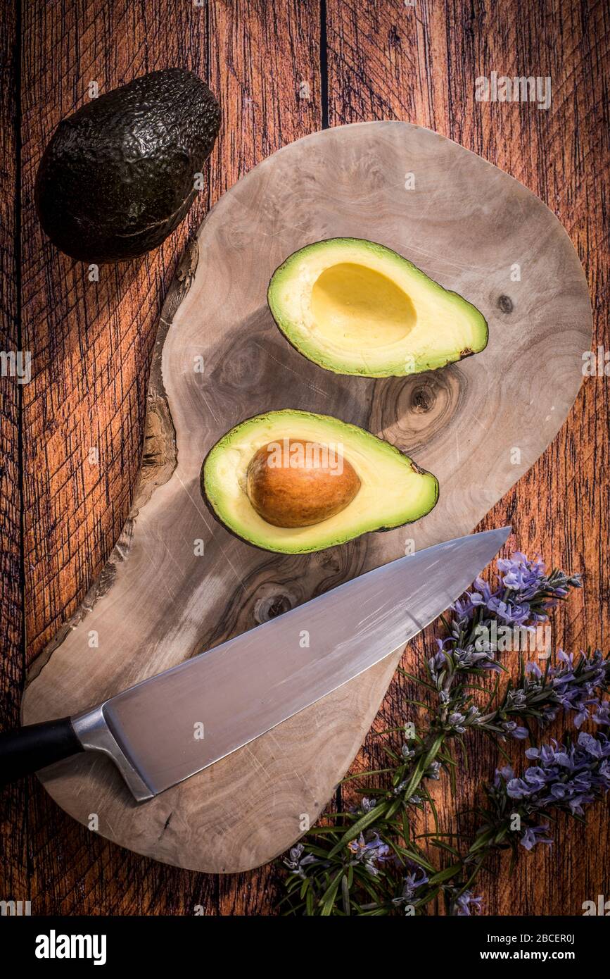 Hass Avocado Birne auf Holzhackbrett auf einem dunklen Holzkitchen Tischplatte, flach gelegt Stockfoto
