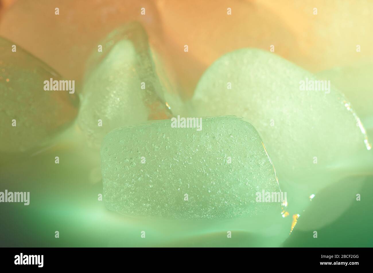 Makro mit grünem Eiswürfel auf verschwommenem farbenfrohen Hintergrund Stockfoto