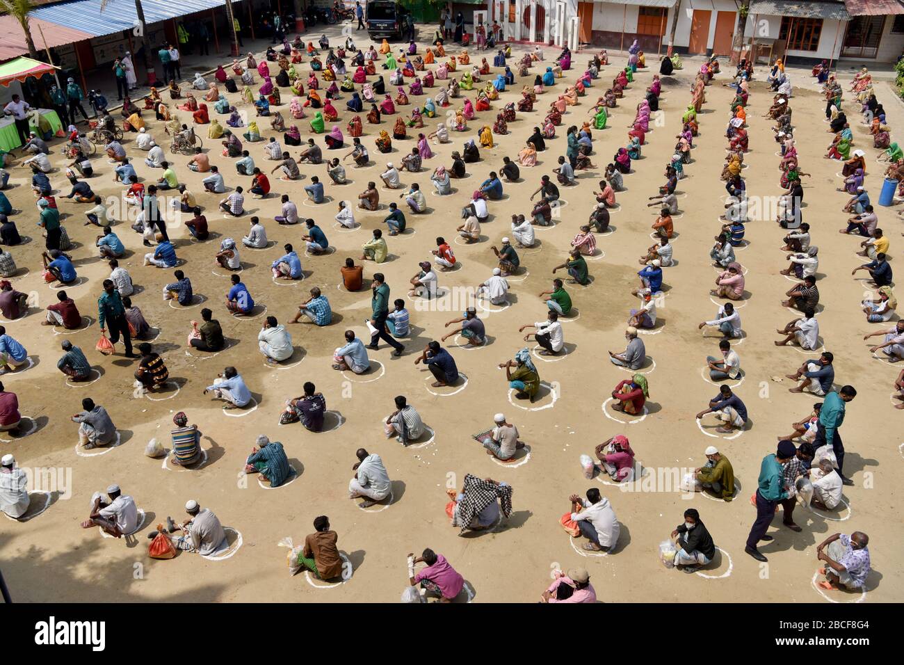 Dhaka, Bangladesch - 04. April 2020: Bangladeschische Obdachlose warten in einer Warteschlange, um Hilfe während der landesweiten Sperre zu erhalten, die als Maßnahme für Vj verhängt wurde Stockfoto