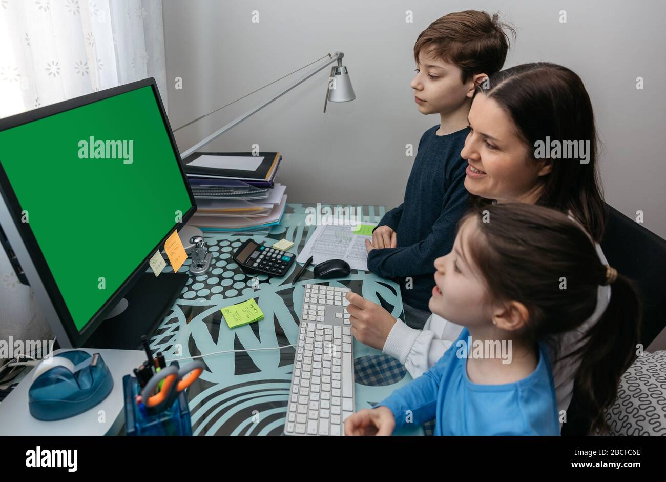 Mutter und Kinder, die auf den Computerbildschirm schauen Stockfoto