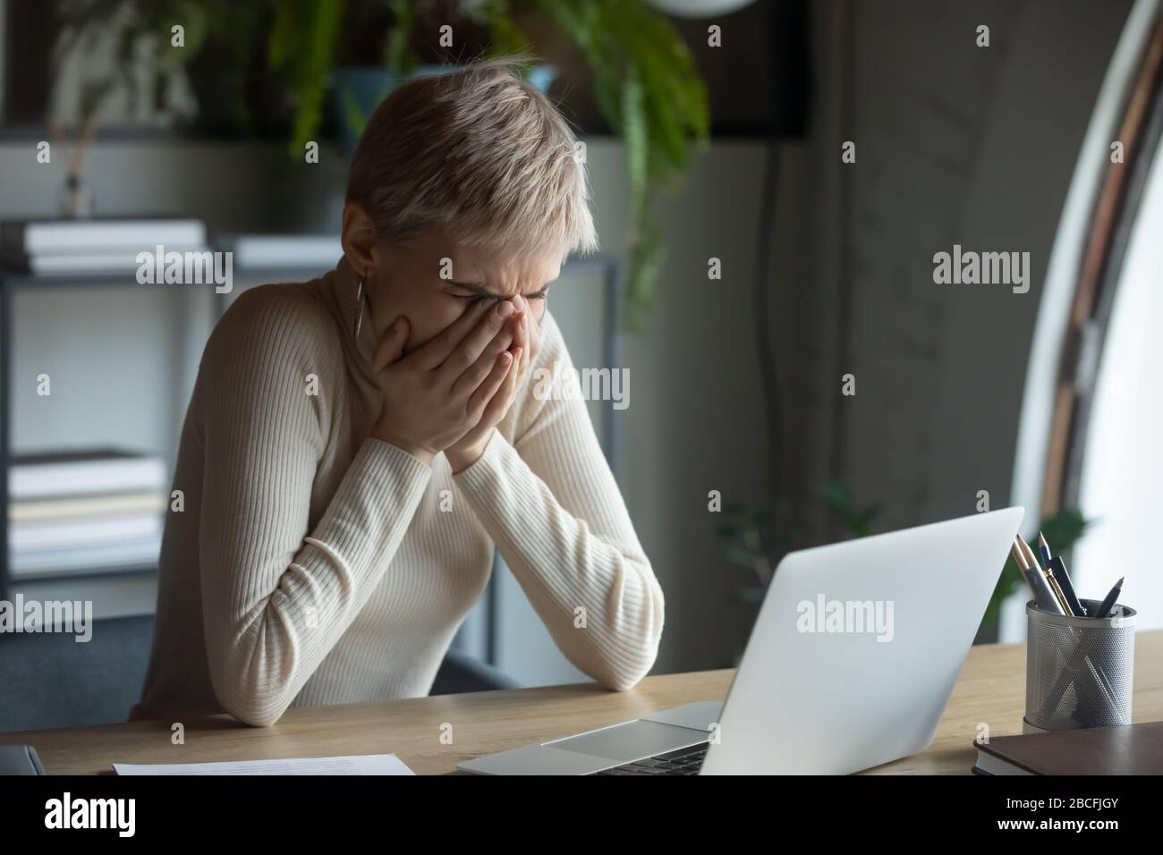 Verunglückte 30er-Dame, die den Mund mit den Händen bedeckt, die niesen oder husten. Stockfoto