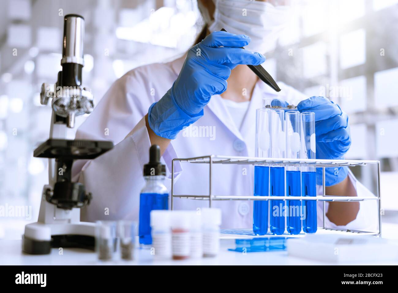 Wissenschaftler, die im Labor im weißen Labormantel recherchieren, Handschuhe analysieren, Reagenzgläser Probe betrachten, Biotechnologiekonzept. Stockfoto