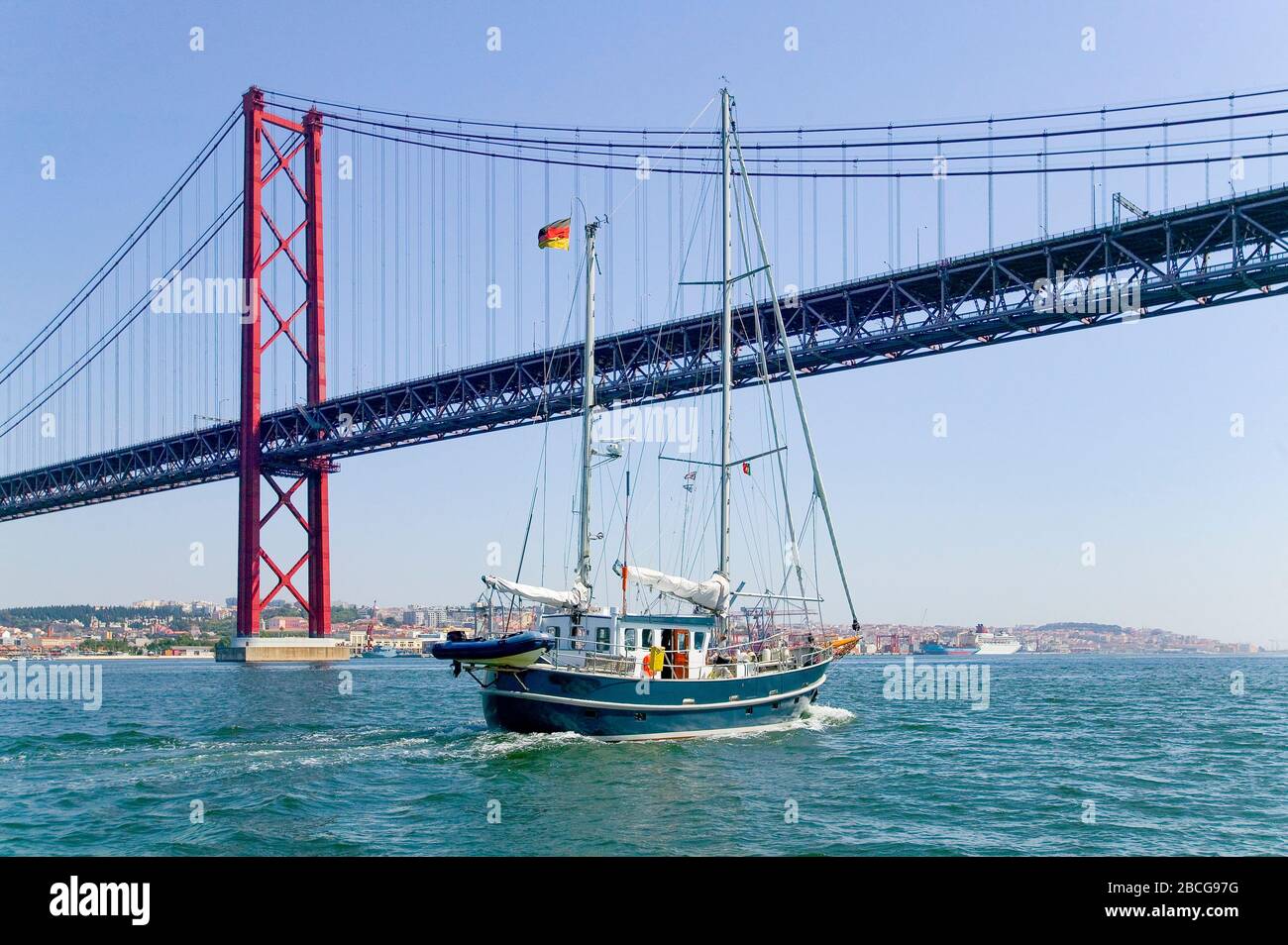 Segelyacht über die Brücke vom 25. April, über den Fluss Tejo in Lissabon, Portugal Stockfoto